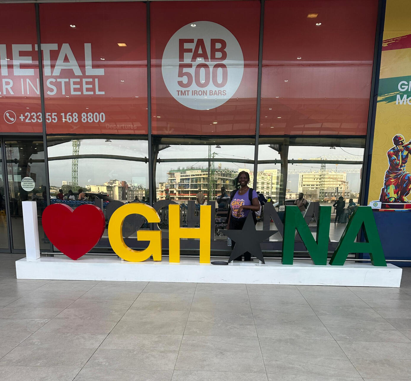 Regina Standing in front of a sing made of large letters saying I Love Ghana